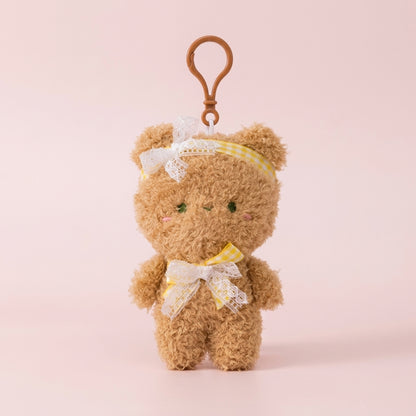 Brown plush teddy bag charm on a soft pink background
