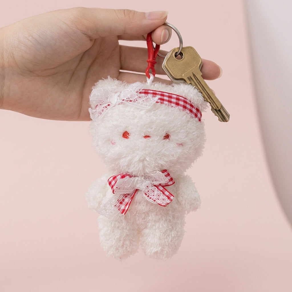 White plush teddy bag charm held in a hand to show its true size